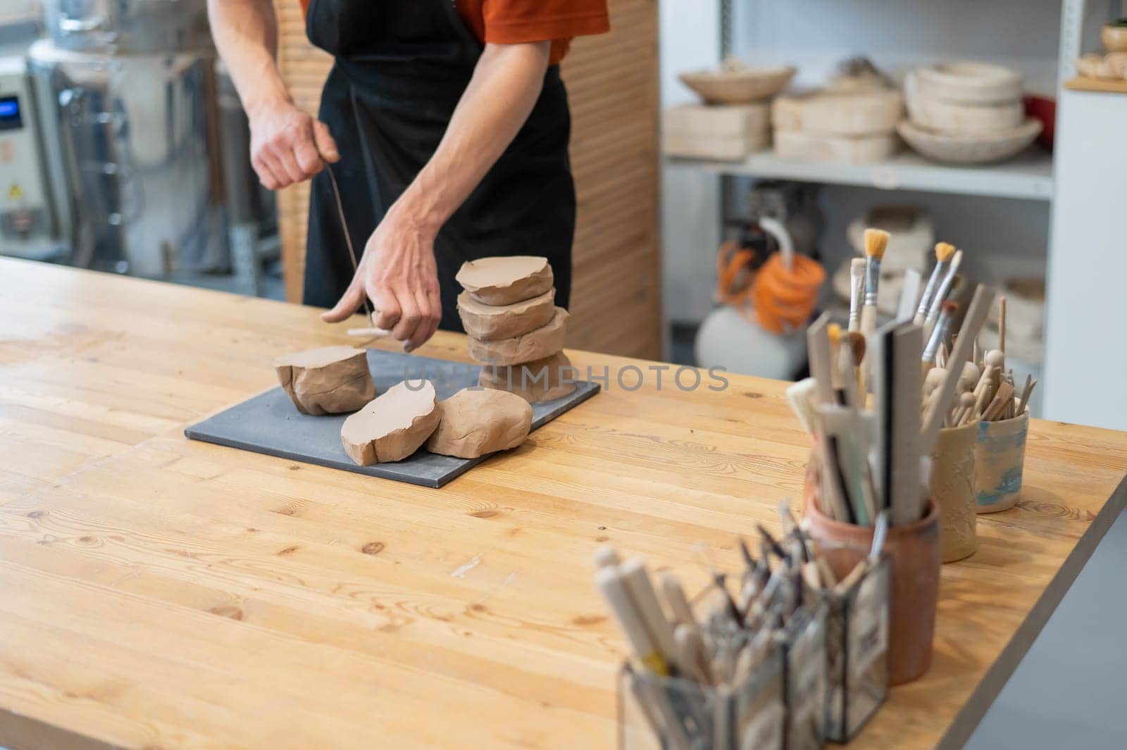 A potter cuts a piece of clay into pieces before using it in the workshop