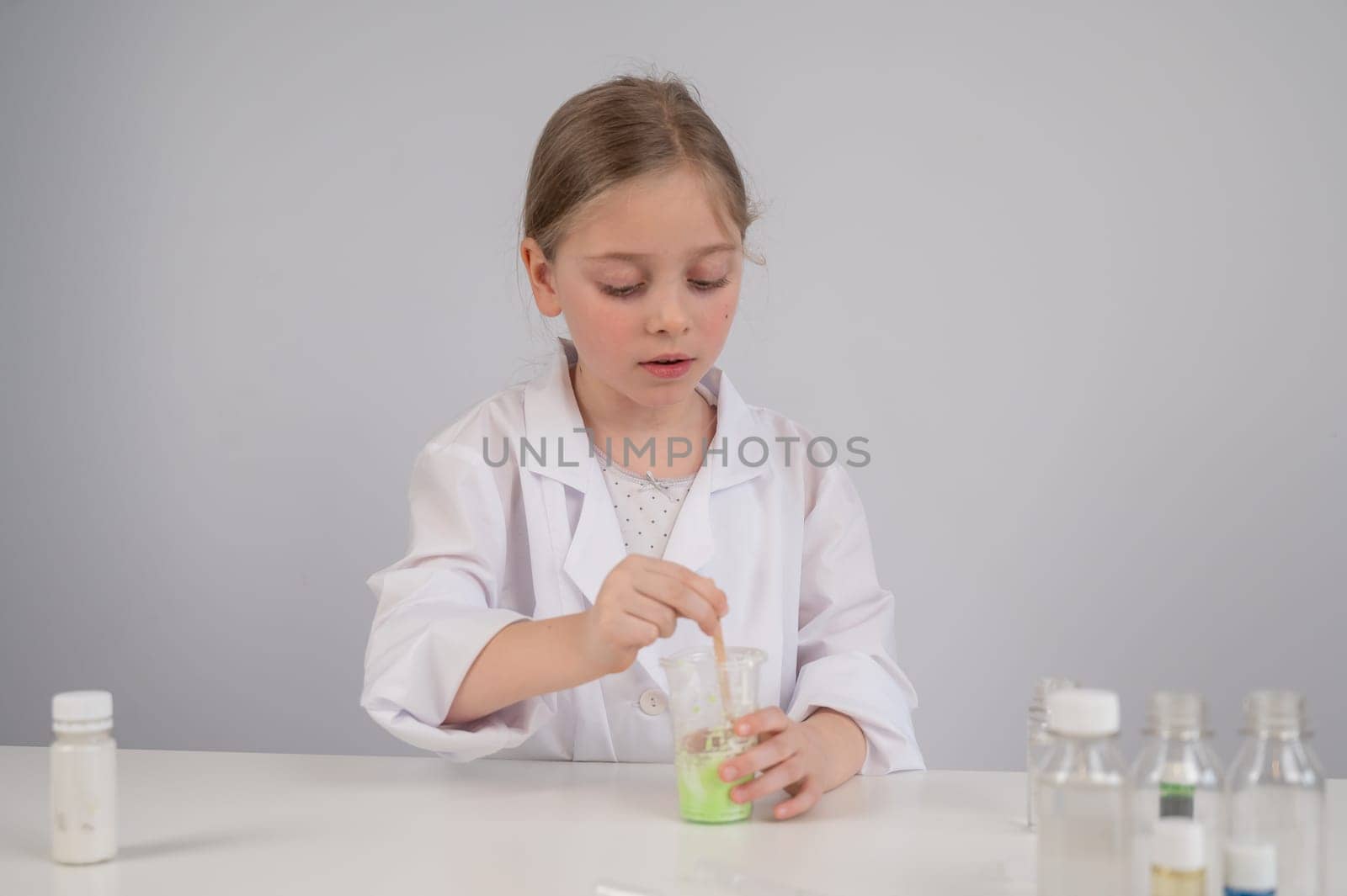 Caucasian girl doing chemical experiments on a white background. Making slime. by mrwed54