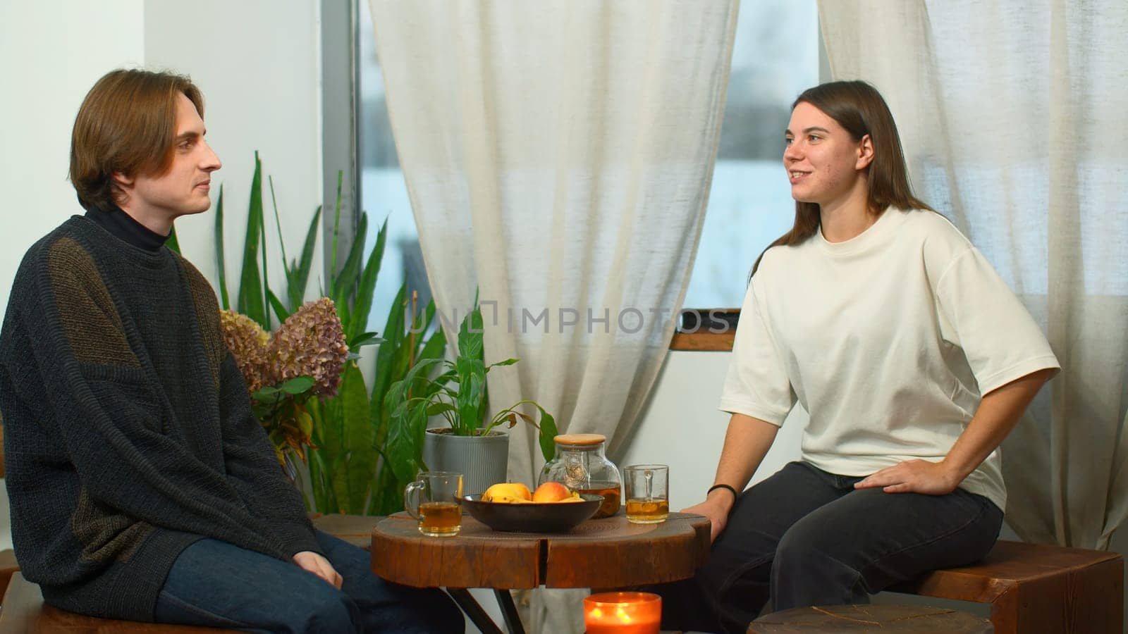 Students communicate and drink tea in cafe. Media. Young man and woman are drinking tea and talking in cafe. Cheerful conversation between young couple of students in cozy cafe.