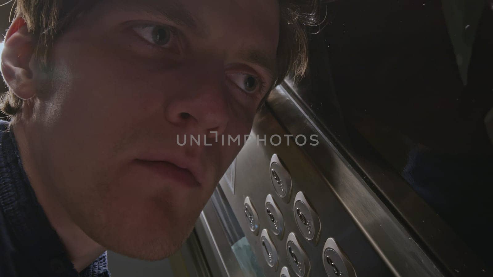 Close up of man listening carefully to the noise of elevator malfunction and pressing the floor button. Stock clip. Men risking to use the faulty elevator. by Mediawhalestock
