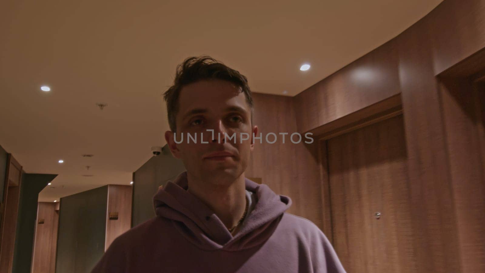 Young man walking in corridor of hotel building. Stock clip. Man in a hall wearing hoodie