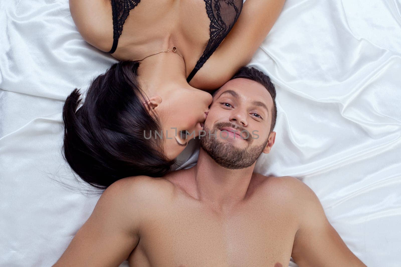 Top view of man pretty smiling while sexy woman kissed him