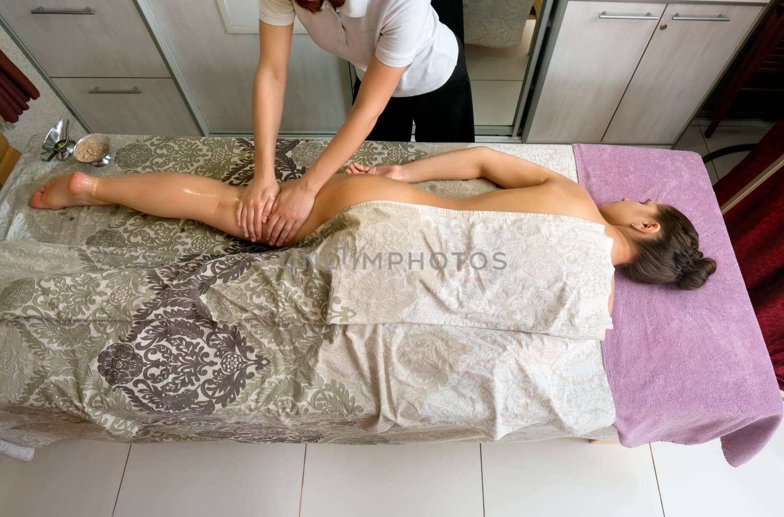 Top view of beautiful woman lying on massage table, therapist massaging her body. Young girl getting spa treatment. Beauty and helth care concept