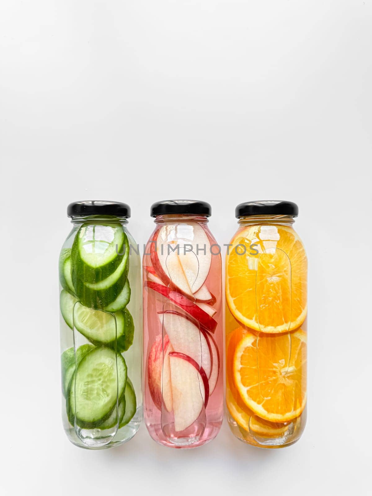 Variety detox drinks in glass bottles on white background, with copy space. Healthy lifestyle and hydration concept for design and print. High quality photo