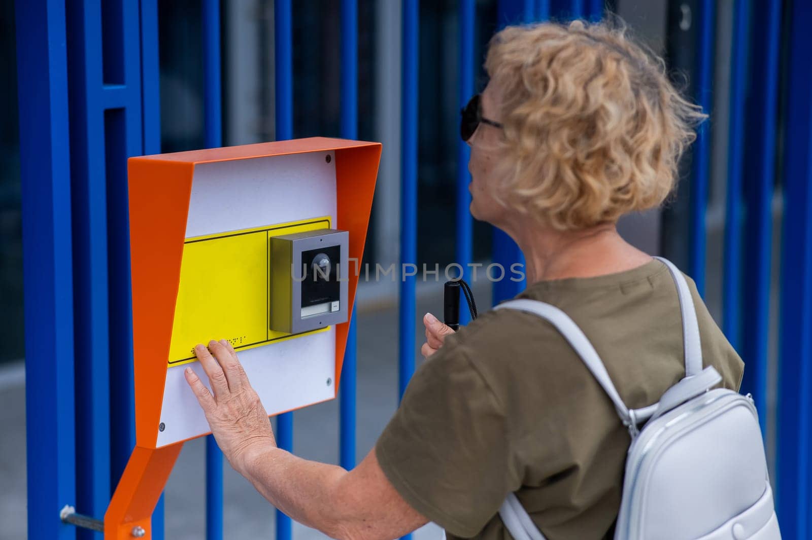 An elderly blind woman reading a text in braille. Button for calling help for people with disabilities