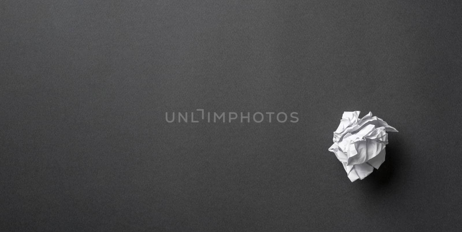 White paper crumpled into a ball on a dark gray background by Sonat