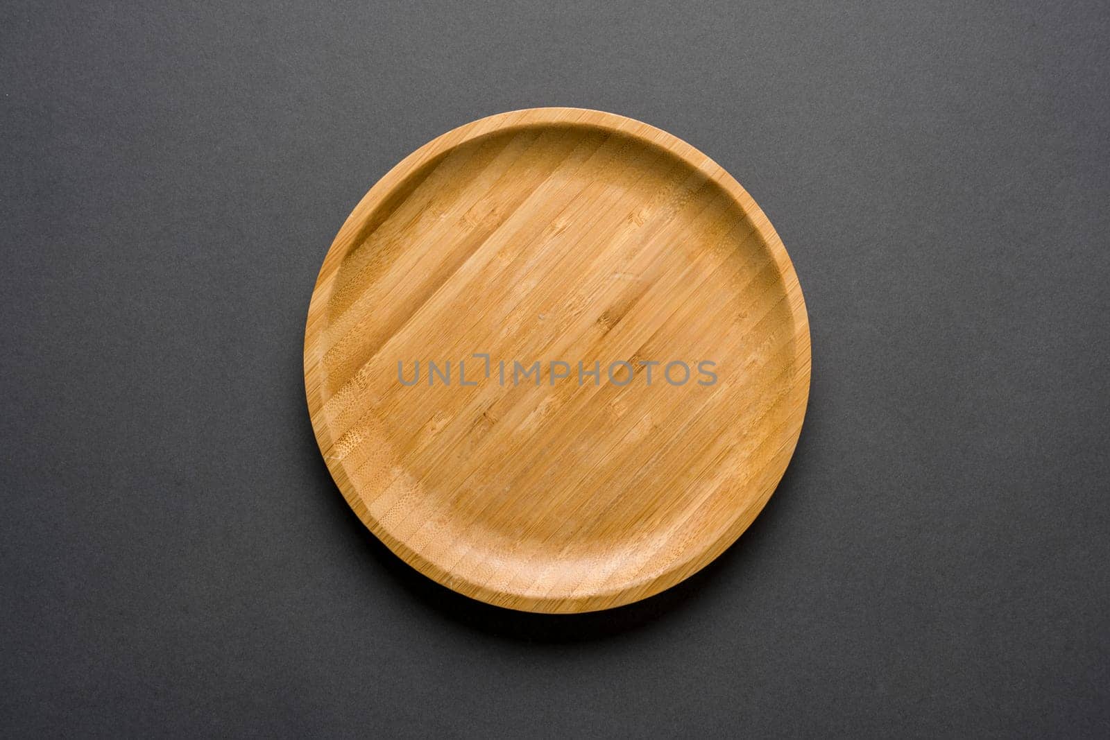 Wooden plate on dark gray background. handmade kitchen utensils by Sonat