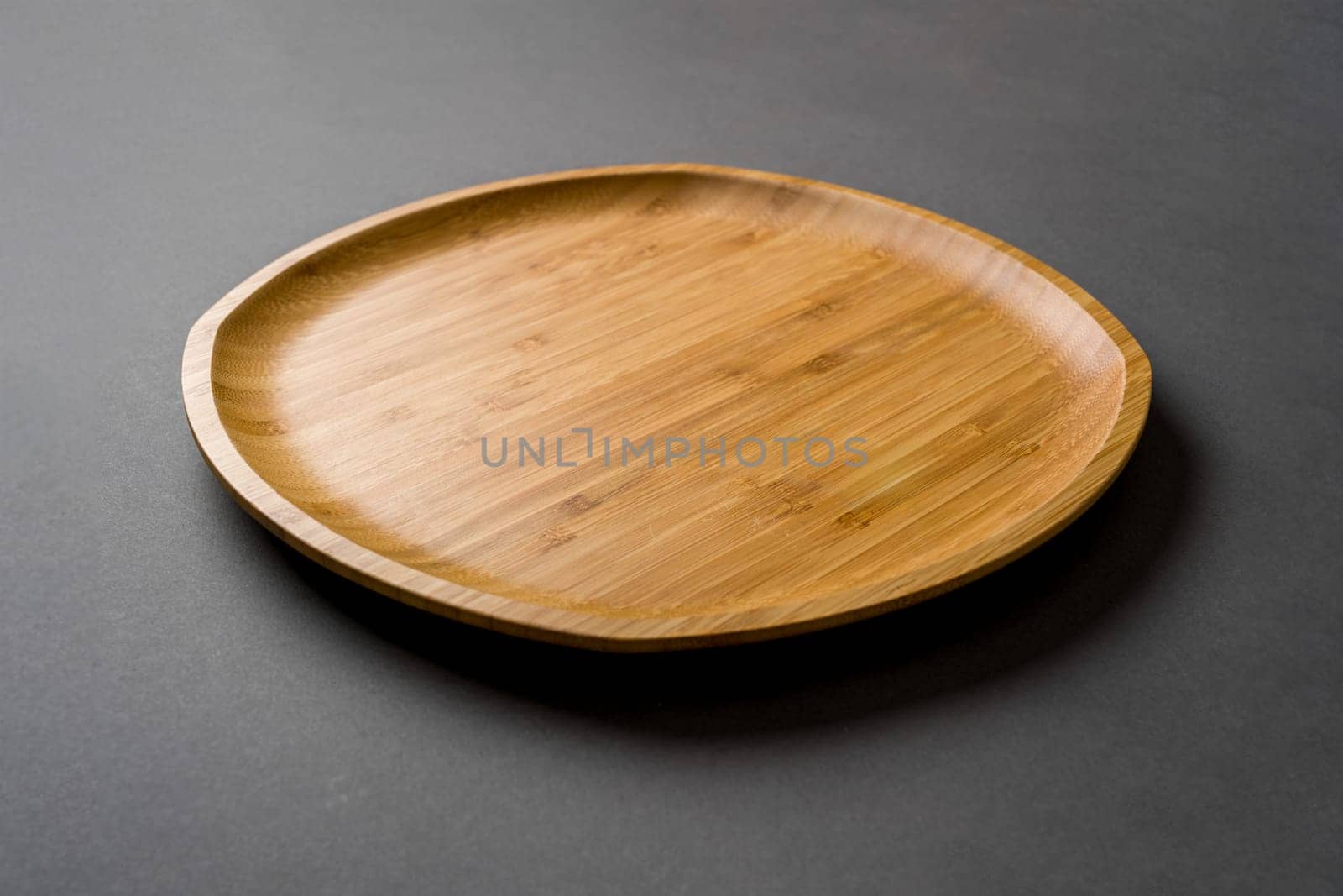 Wooden plate on dark gray background. handmade kitchen utensils by Sonat