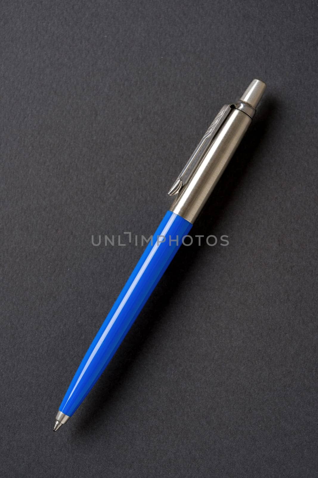 Blue plastic and metal ballpoint pen on dark gray isolated background by Sonat