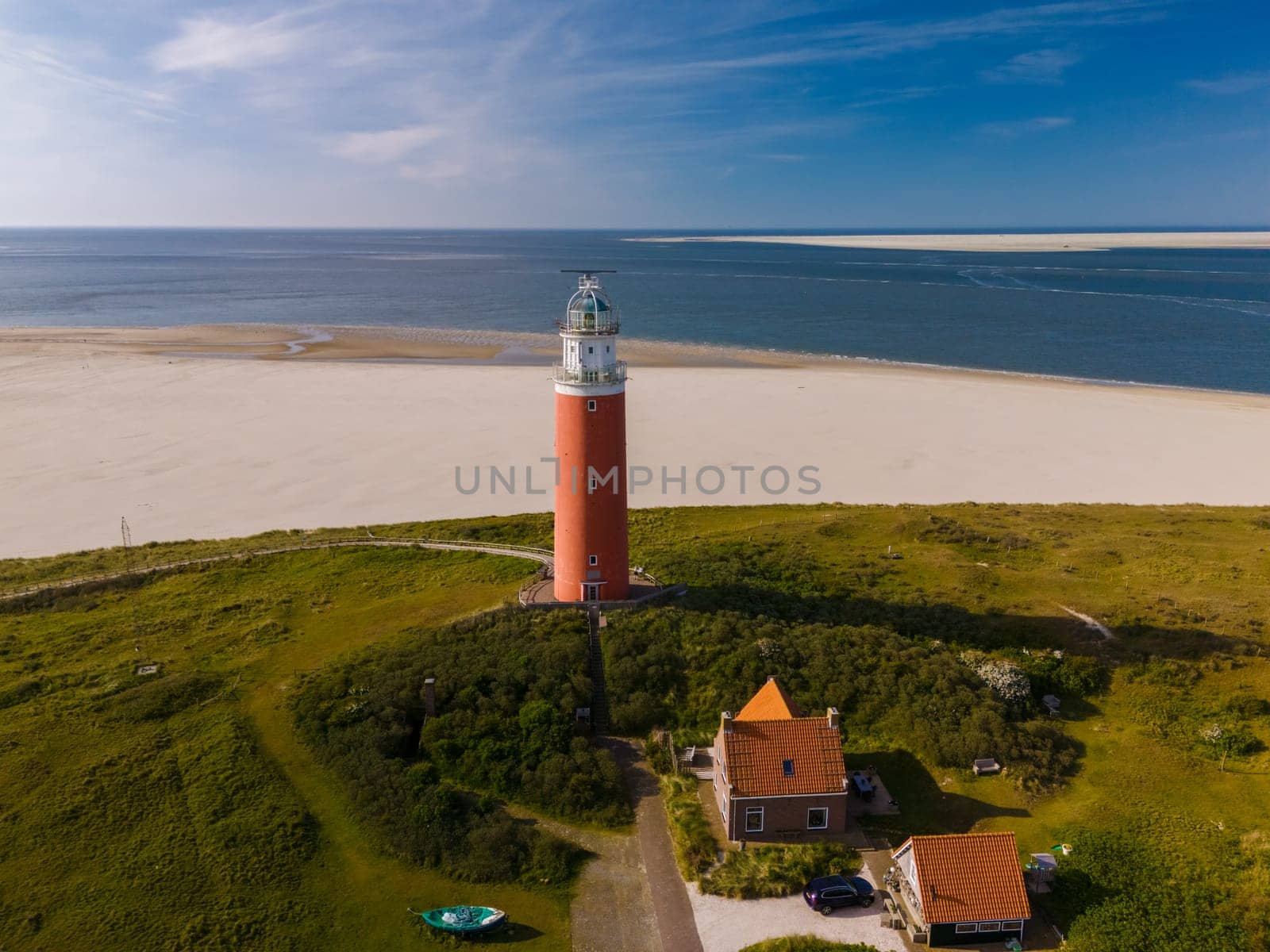 A birds-eye view of a majestic lighthouse standing tall on the sandy beach, its beacon shining brightly on the Texel coast.