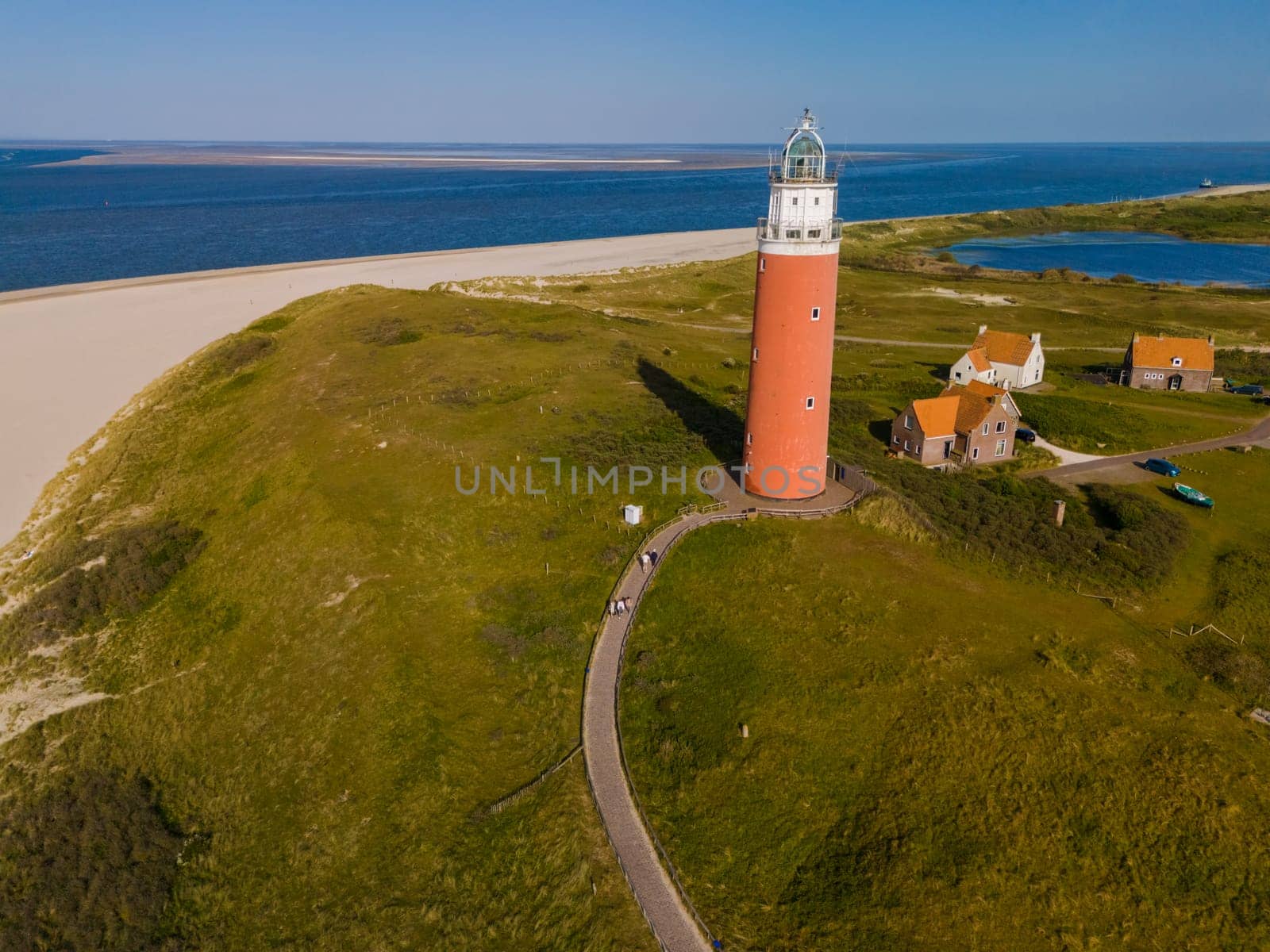 Majestic lighthouse towering over sandy shores, overlooking the vast sea below, guiding ships safely through the night.