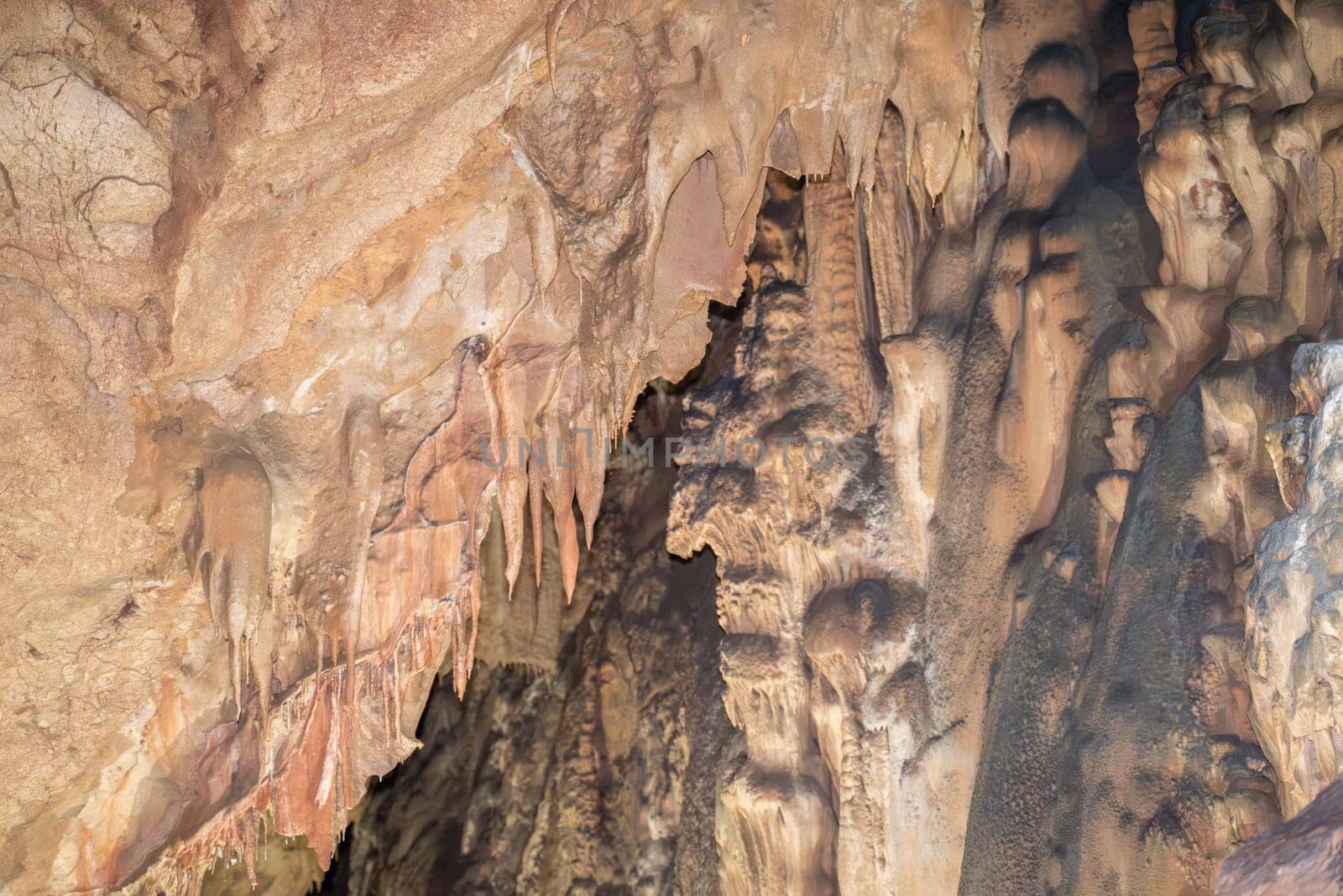 A cave with a lot of rock formations and stalactites hanging from the ceiling. Scene is mysterious and awe inspiring. by Matiunina