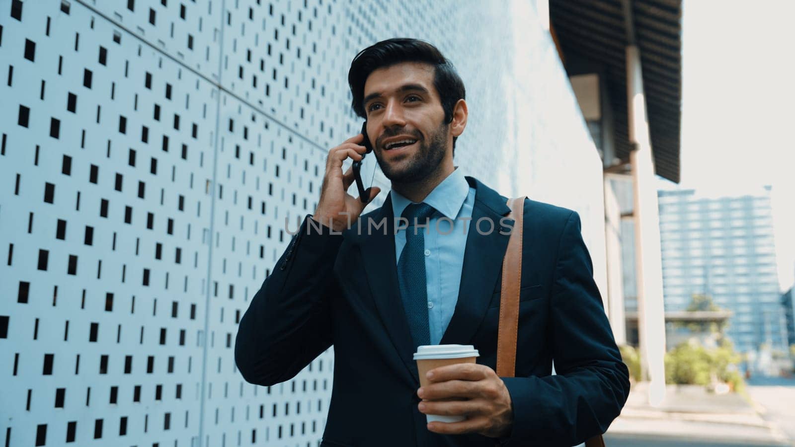 Smart business man using phone to talking about business investment. Happy manager walking at street while talking on smart phone to discuss business plan or marketing strategy or working. Exultant.