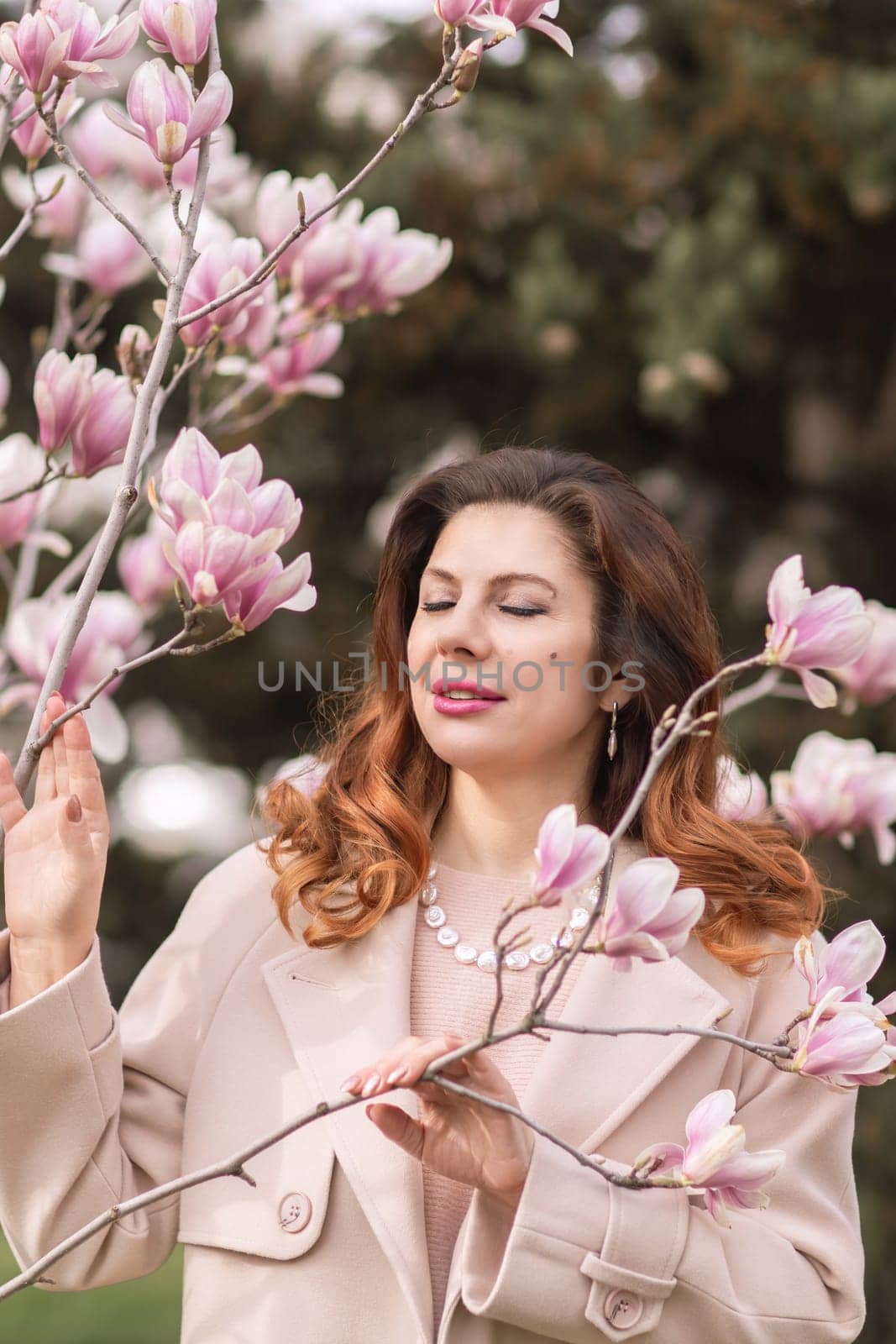 Woman magnolia flowers, surrounded by blossoming trees, hair down, wearing a light coat. Captured during spring, showcasing natural beauty and seasonal change