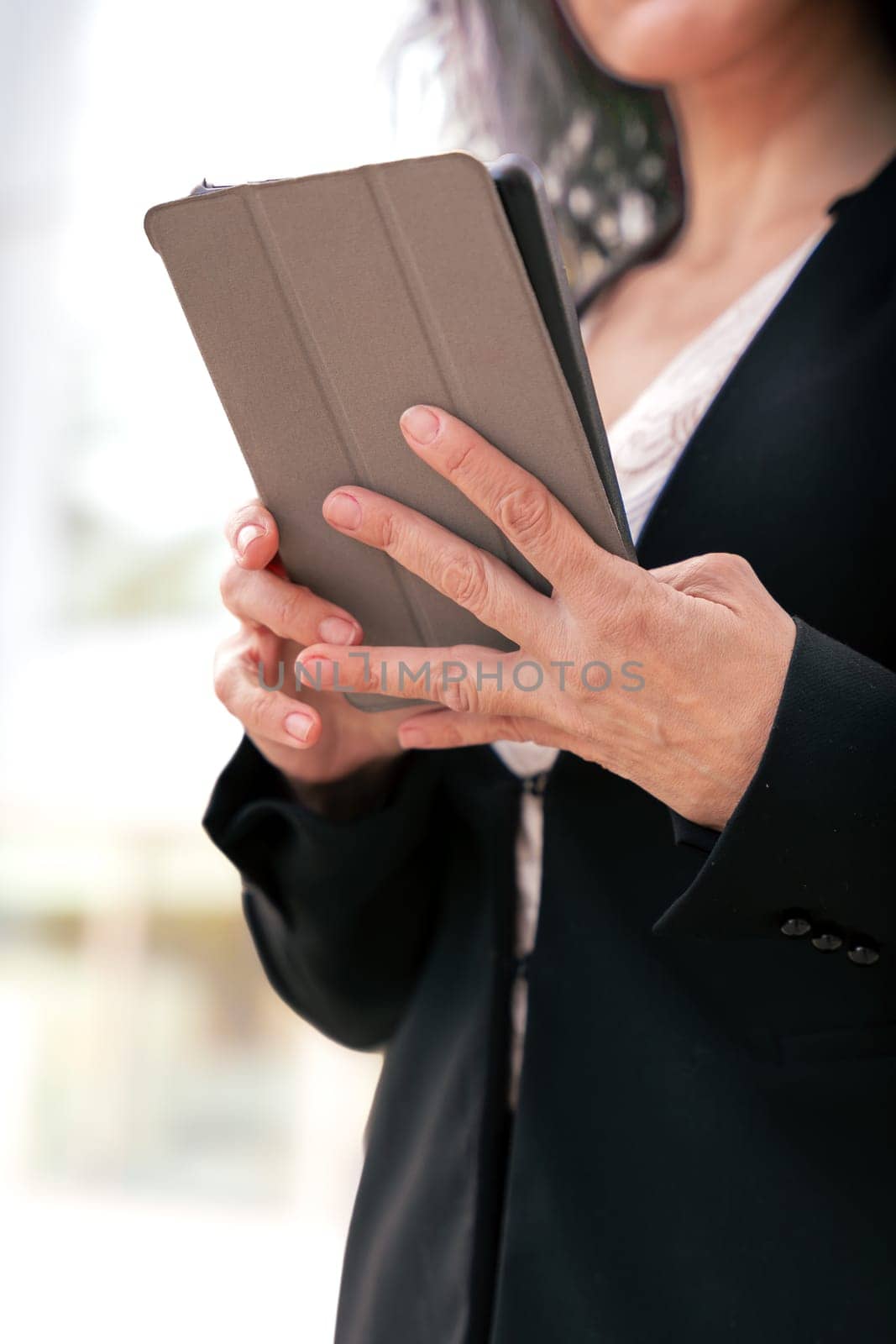 Portrait of a smiling middle-aged business woman with digital tablet in smiling hands looking at camera