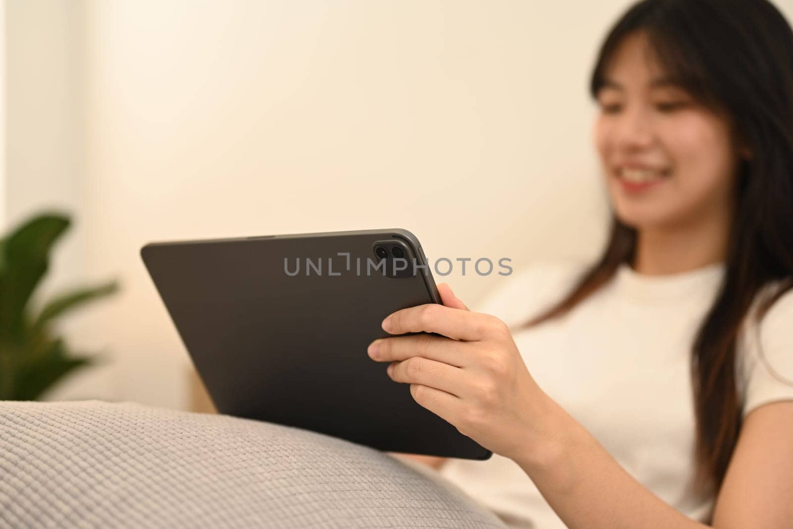 Select focus on woman hands holding digital tablet sitting on bed at home.