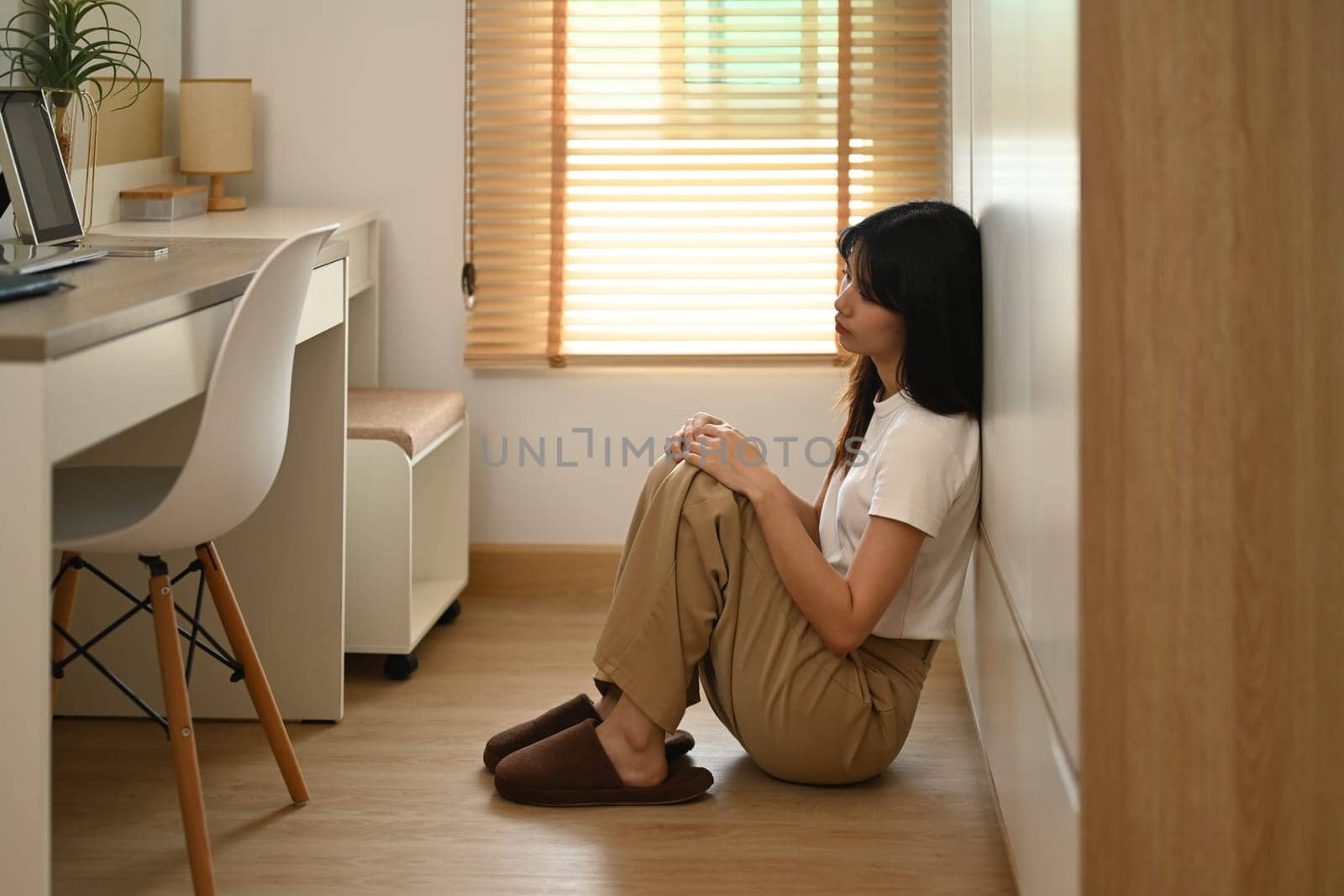 Sad and depressed young woman sitting alone on floor at home. Mental health concept.