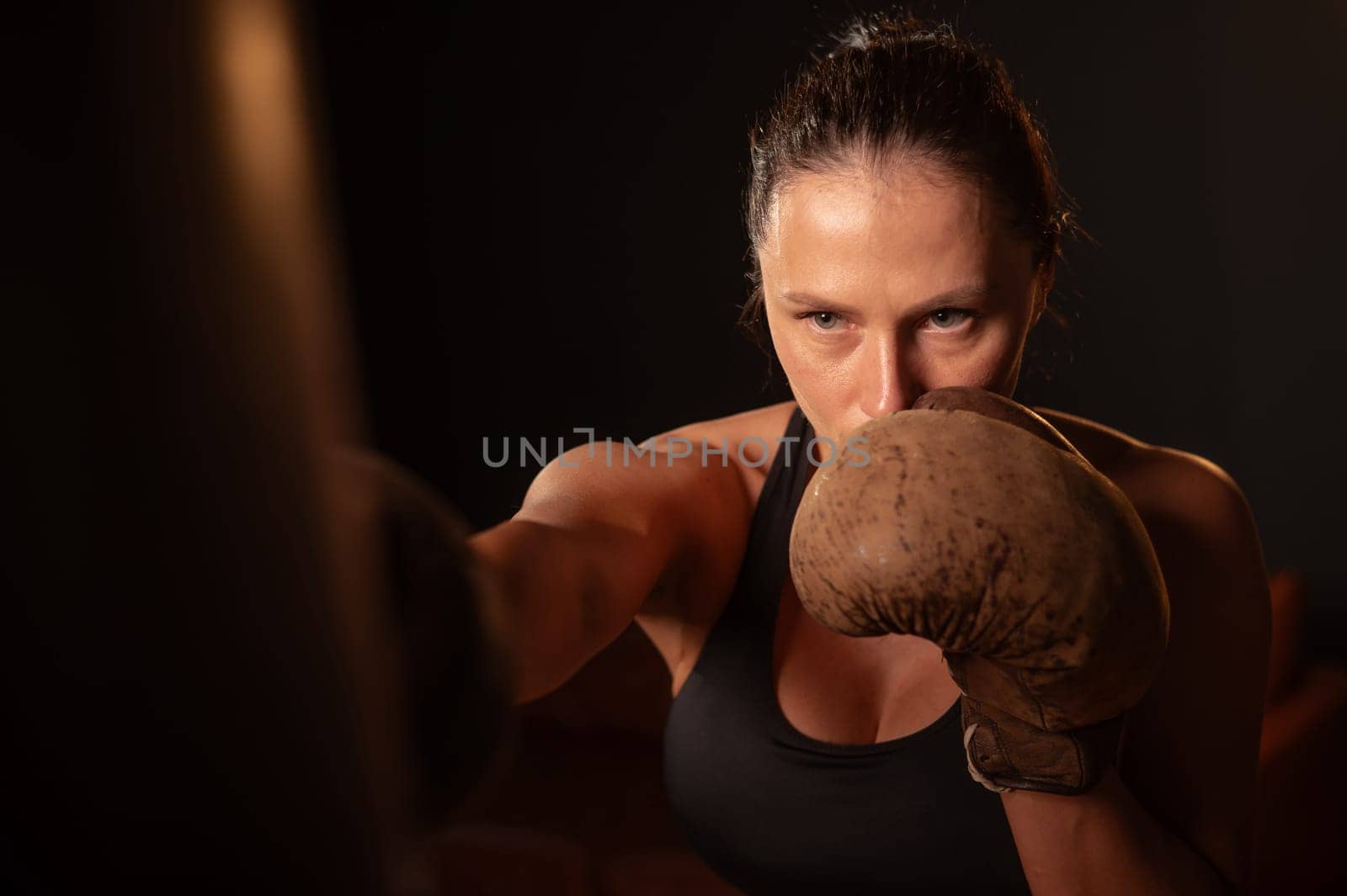 Caucasian woman boxing in retro gym