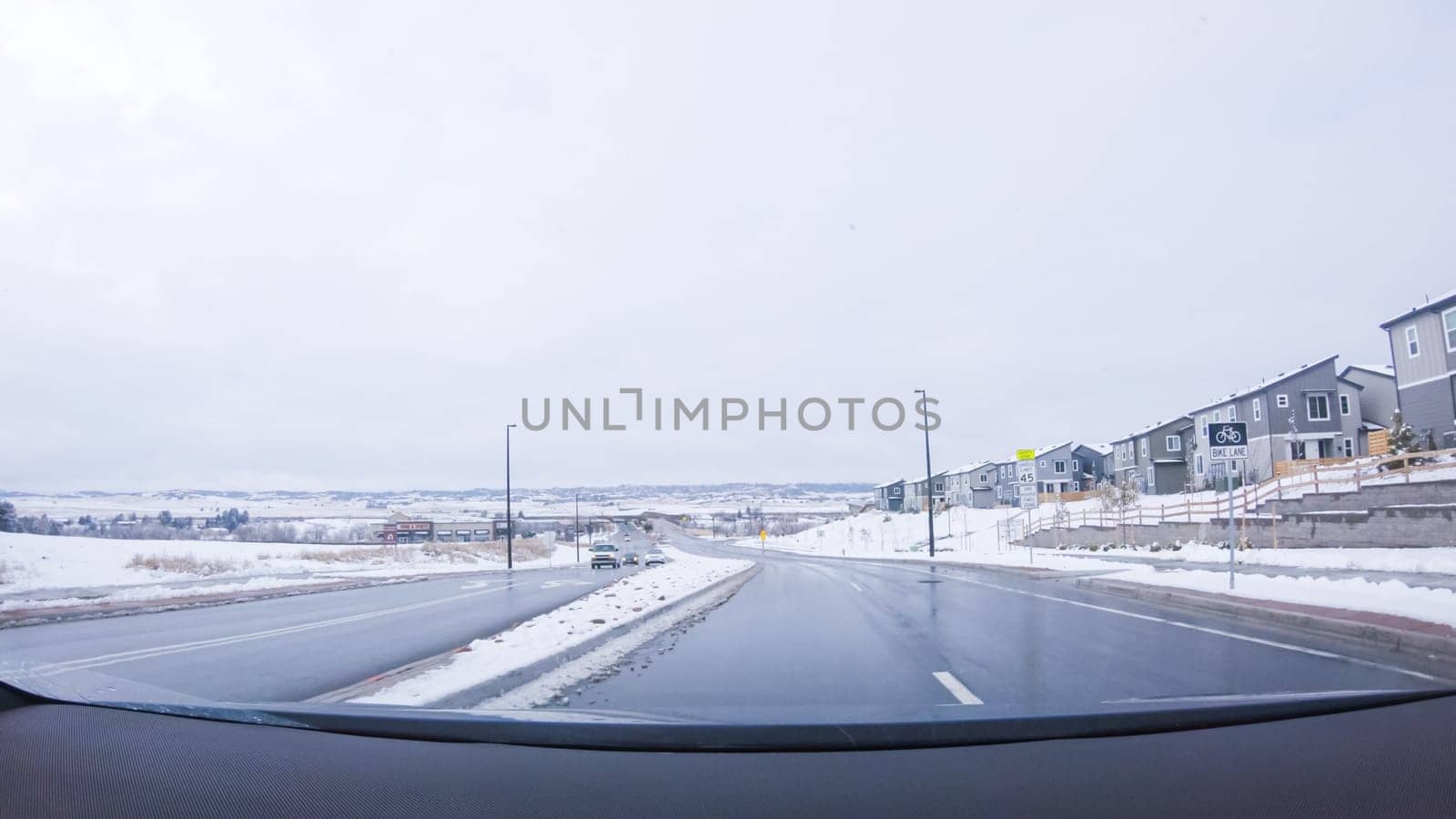 Denver, Colorado, USA-January 26, 2024-The early morning brings a quiet drive through a newly built suburban neighborhood, with fresh snow blanketing the road and houses under a still-dark sky.