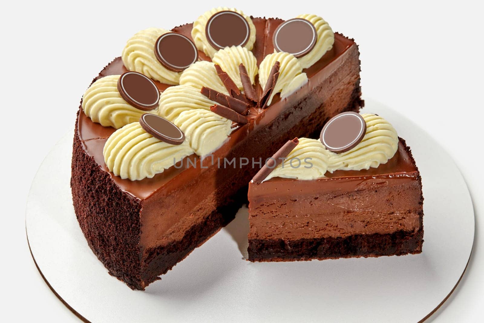 Luxurious coffee cream cheesecake with moist chocolate sponge base and glossy ganache, topped with elegant vanilla cream swirls and chocolate shavings, presented on white background