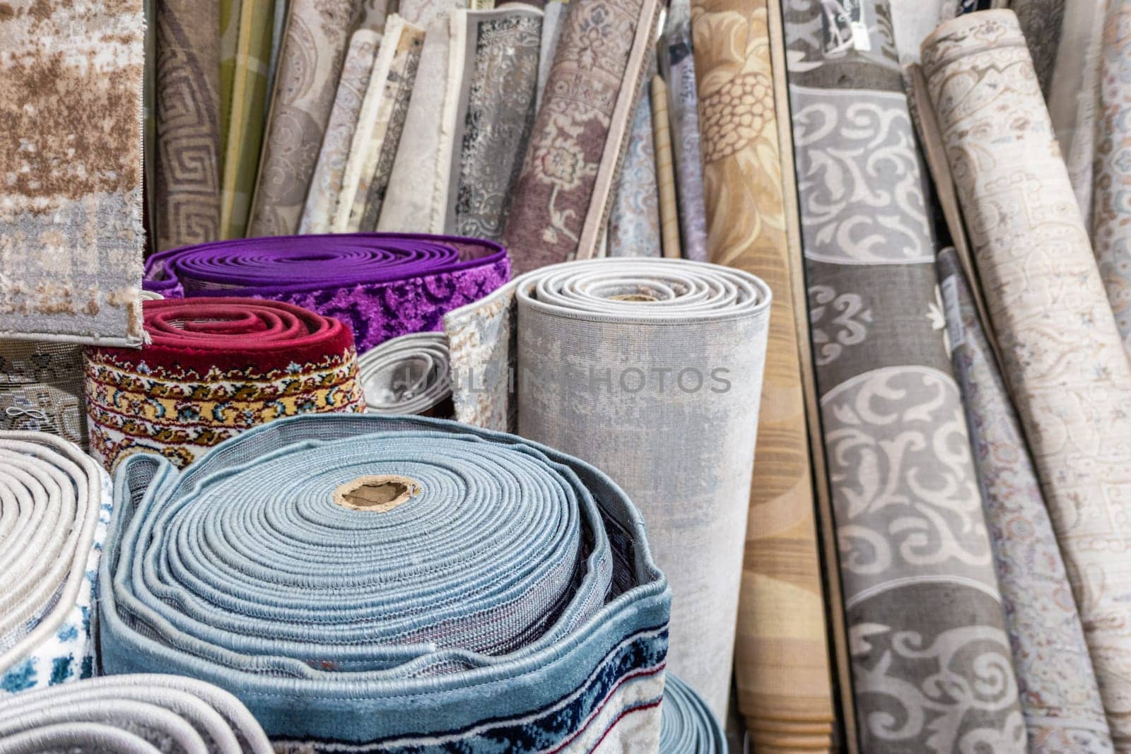 Many rolled carpets in Asian carpet store and carpet warehouse. Full-frame closeup background.