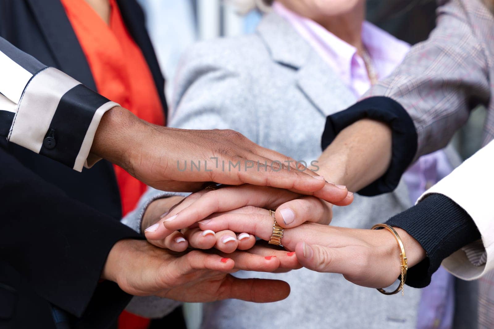 Unrecognizable close-up of diverse businesswomen clasping hands outdoors. by mariaphoto3