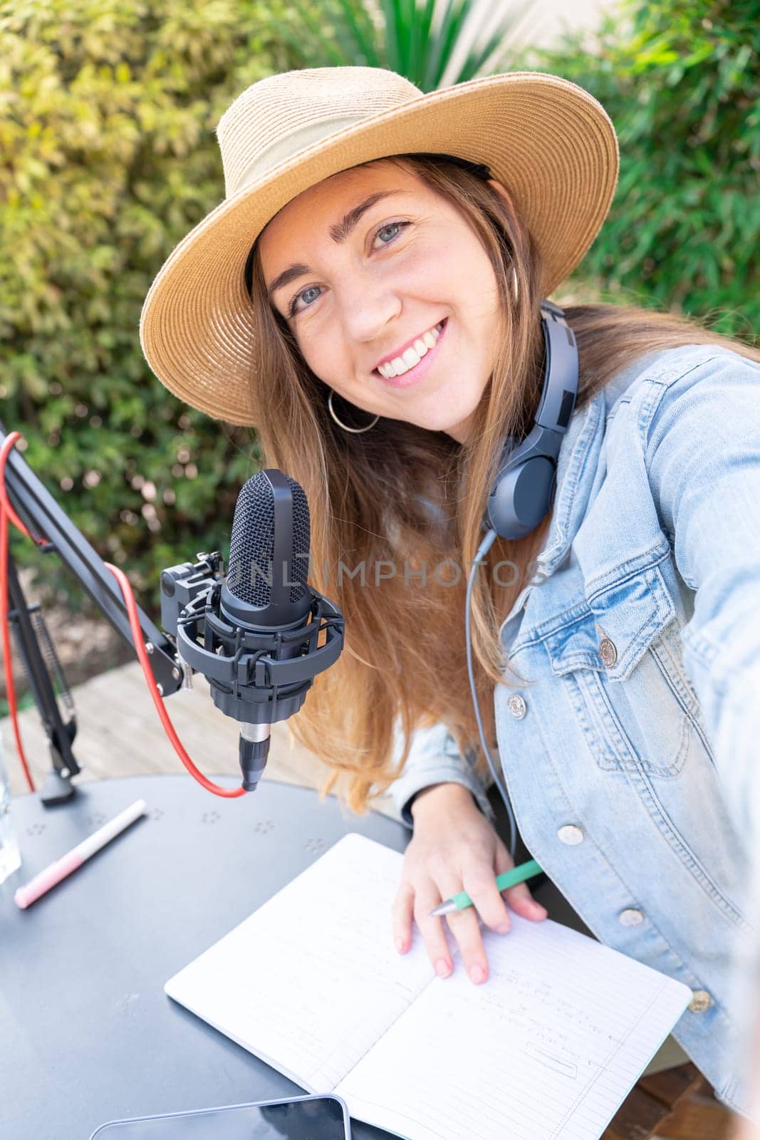 Selfie of a happy smiling young woman with headphones recording podcast. by PaulCarr