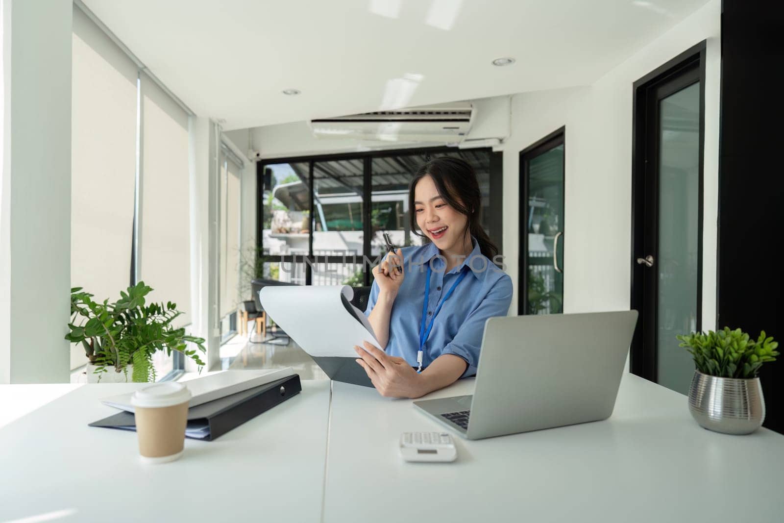 Asian Businesswoman Reviewing Documents at Desk. Concept of Productivity and Professionalism.