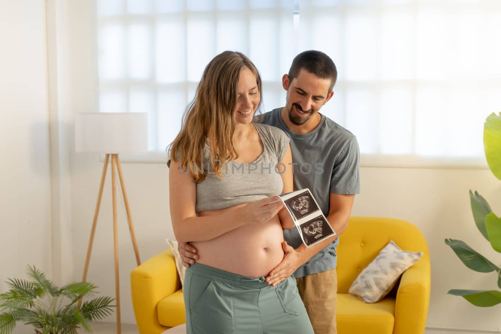 Pregnancy couple looking picture of ultrasound, smiling happily touching belly. High quality photo