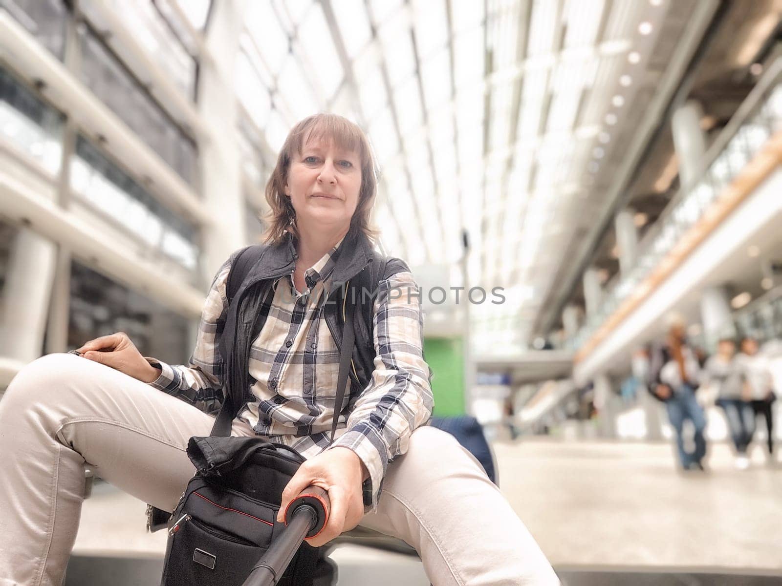 Middle-Aged Woman Taking Selfie at Airport Before Departure. A middle-aged woman captures selfie in an airy airport terminal