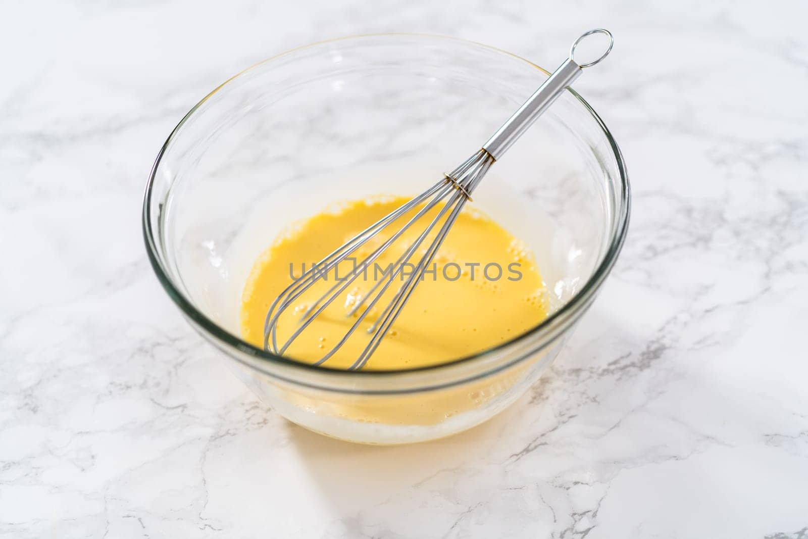 Mixing wet ingredients in a large glass mixing bowl to bake eggnog cookies with a chocolate gingerbread man.