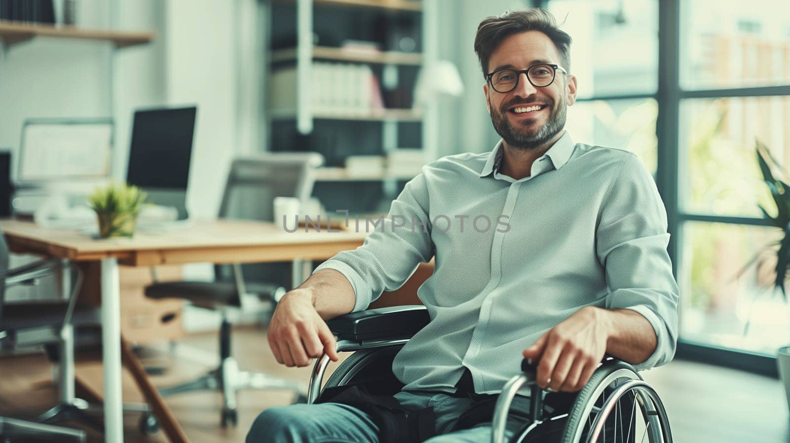 Happy smiling disabled employee man sitting in a wheelchair working at workplace in modern office