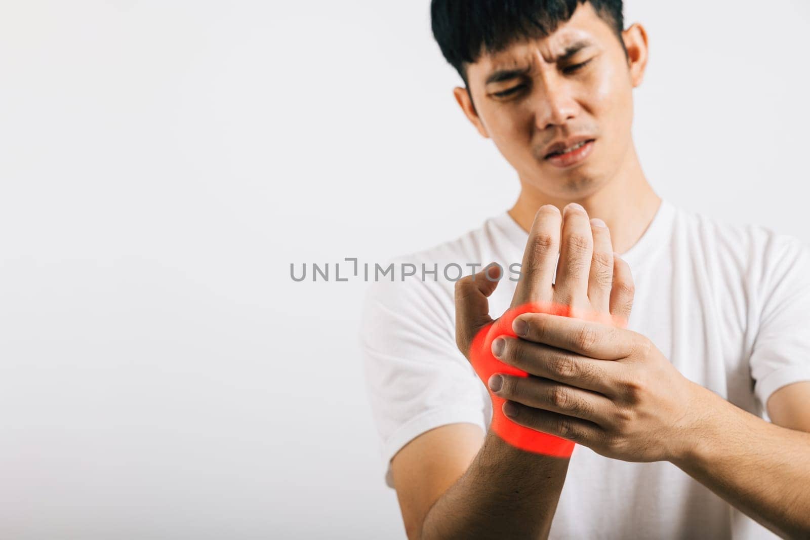 Portrait of a young Asian man dealing with palm and hand pain, massaging his aching hands. Studio shot isolated on white, emphasizing health care and arthritis treatment.