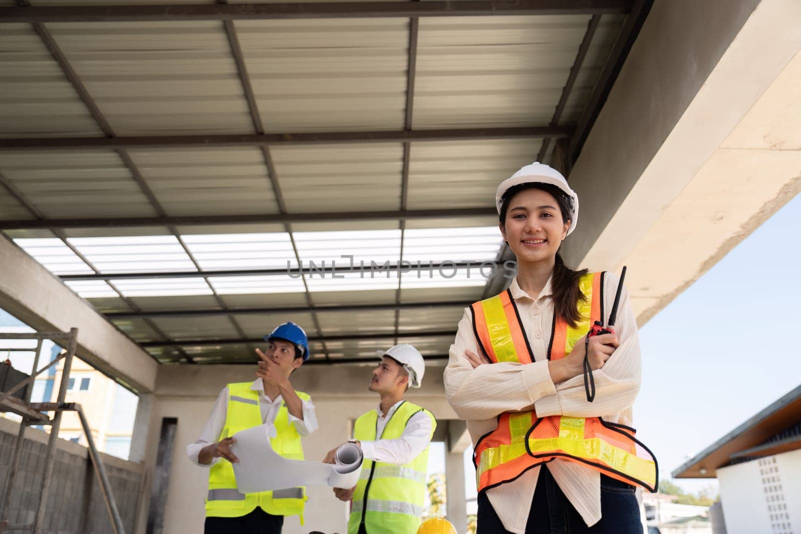 Confident Asian female engineer with colleagues at construction site, leadership concept.