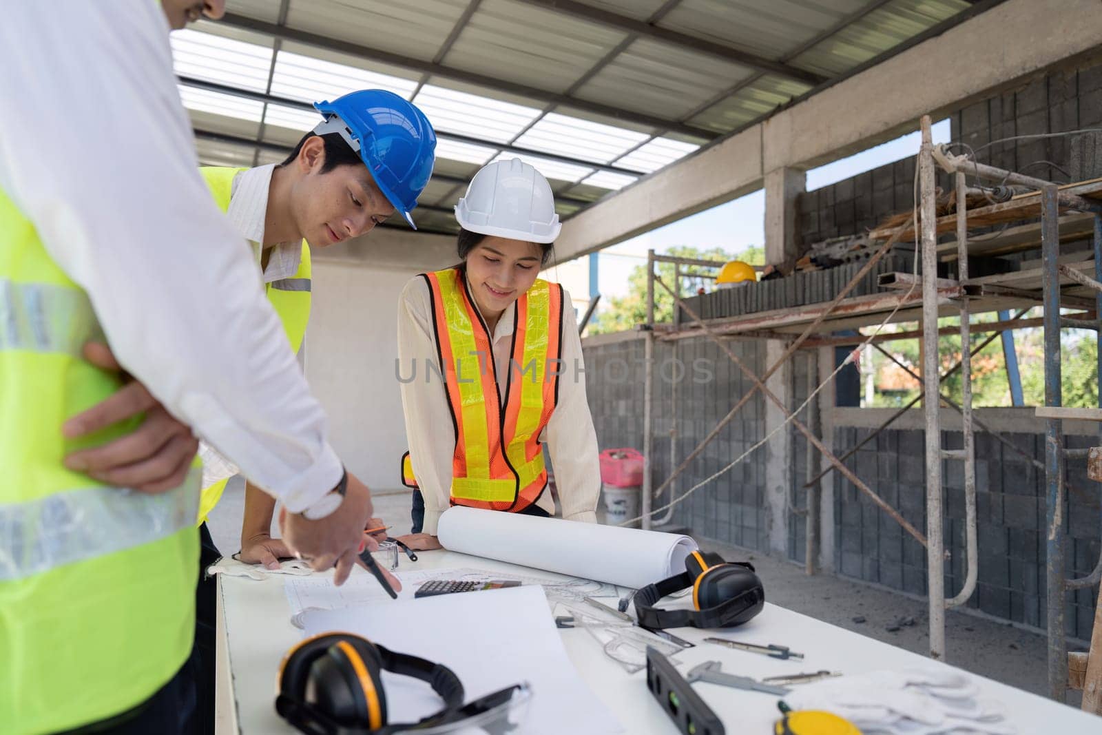 Team of engineer reviewing discussion blueprint at construction site, collaborative planning.