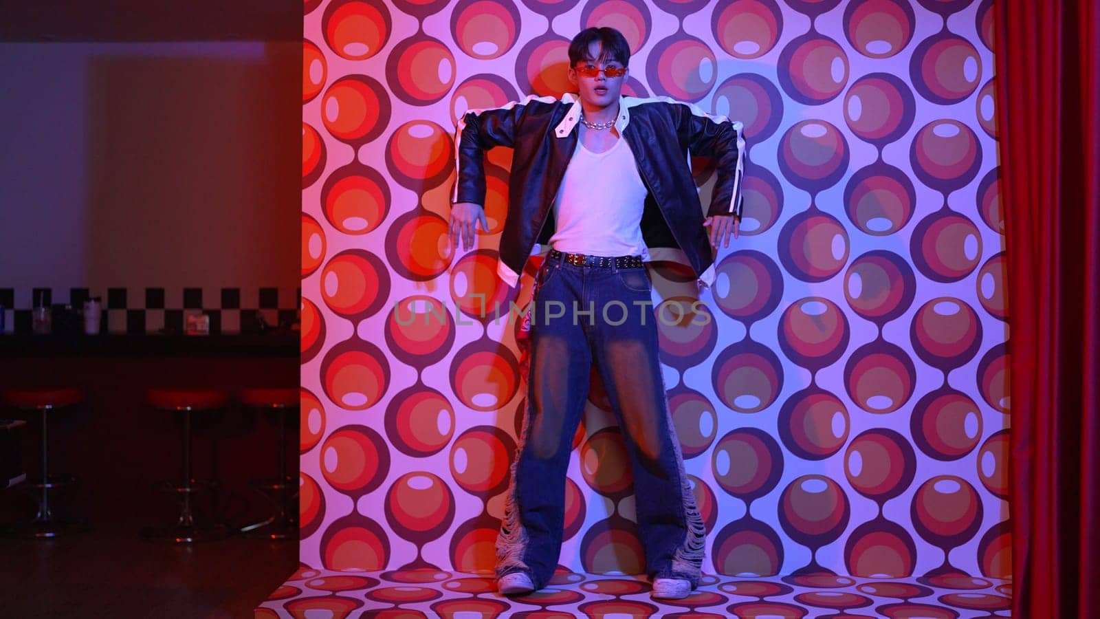 Asian break dancer moving to freestyle music and looking at camera at stage with balloon background. Professional hipster wearing casual outfit and fancy glasses while perform footstep. Regalement.