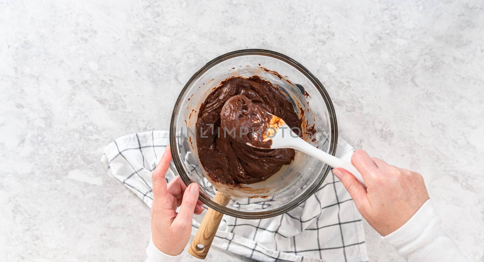 Flat lay. Melting white chocolate chips and other ingredients in a glass mixing bowl over boiling water to prepare chocolate macadamia fudge.