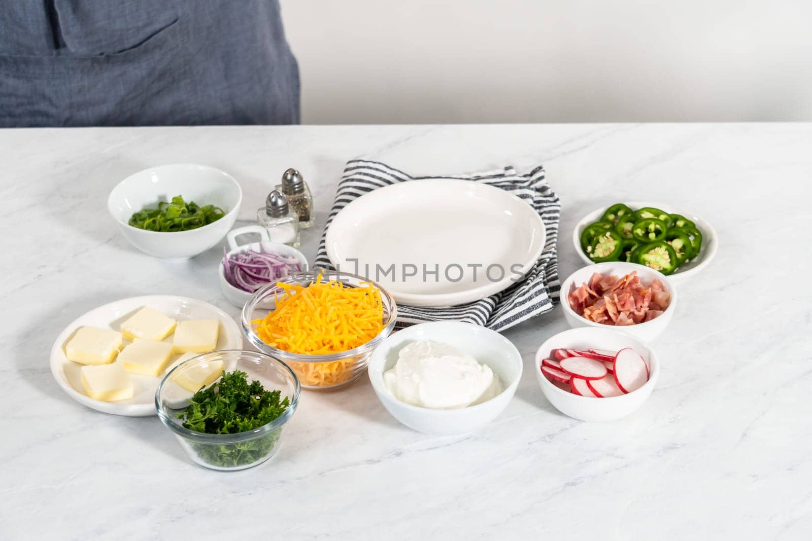 Pressure Cooker Baked Potatoes. Garnished large baked potatoes with butter, sour cream, cheese, and bacon bits on a white plate.