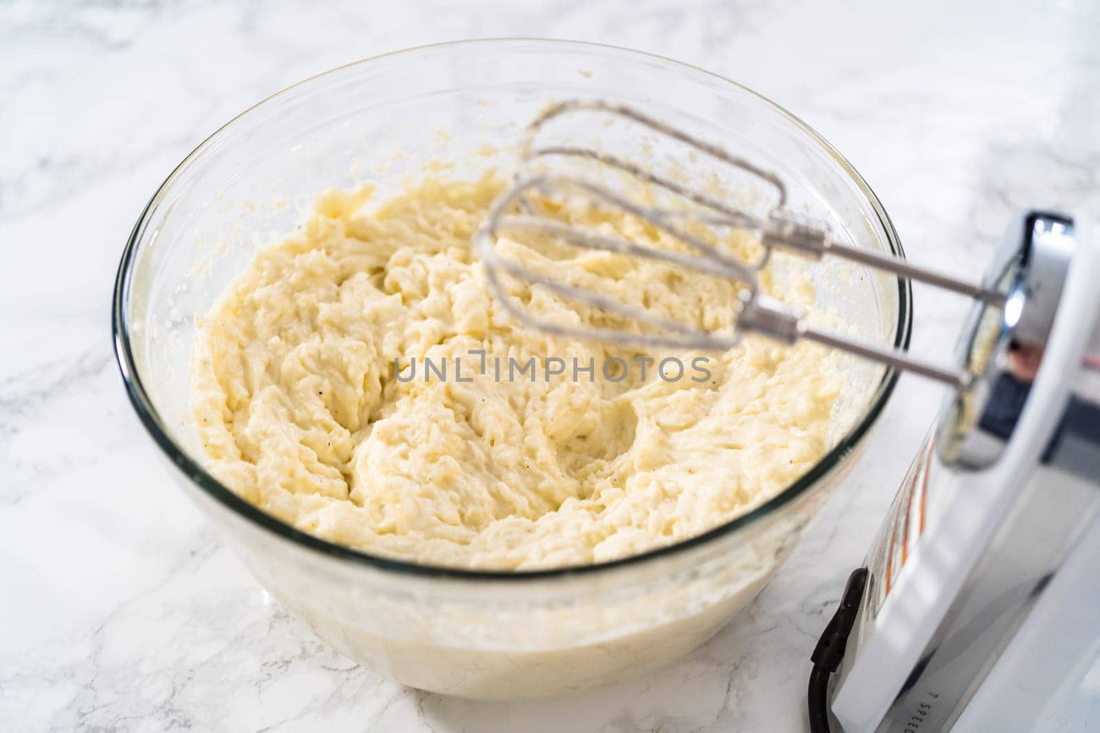 Mashed potatoes. Mashing cooked potatoes in a glass mixing bowl with a hand mixer made creamy mashed potatoes.