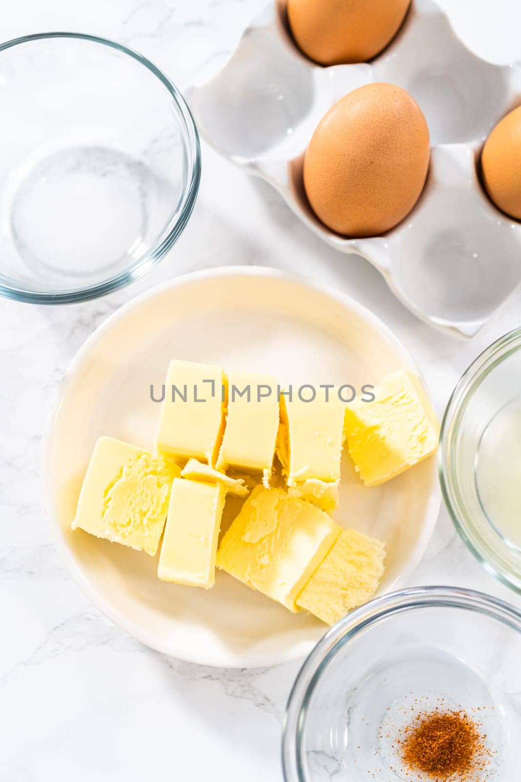 Measured ingredients in glass mixing bowls to prepare hollandaise sauce.