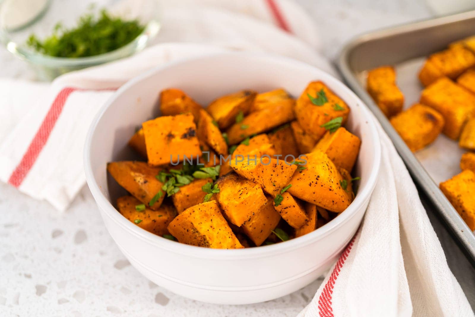 Serving oven-roasted sweet potatoes in a white ceramic bowl.