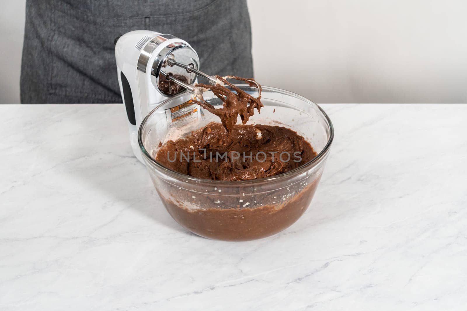 Mixing ingredients in a large glass mixing bowl to bake red velvet bundt cake with cream cheese glaze.