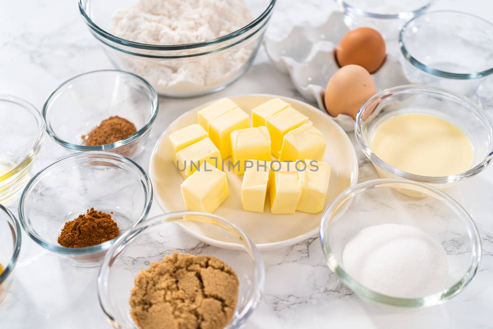 Measured ingredients in glass mixing bowls to bake eggnog cookies with a chocolate gingerbread man.