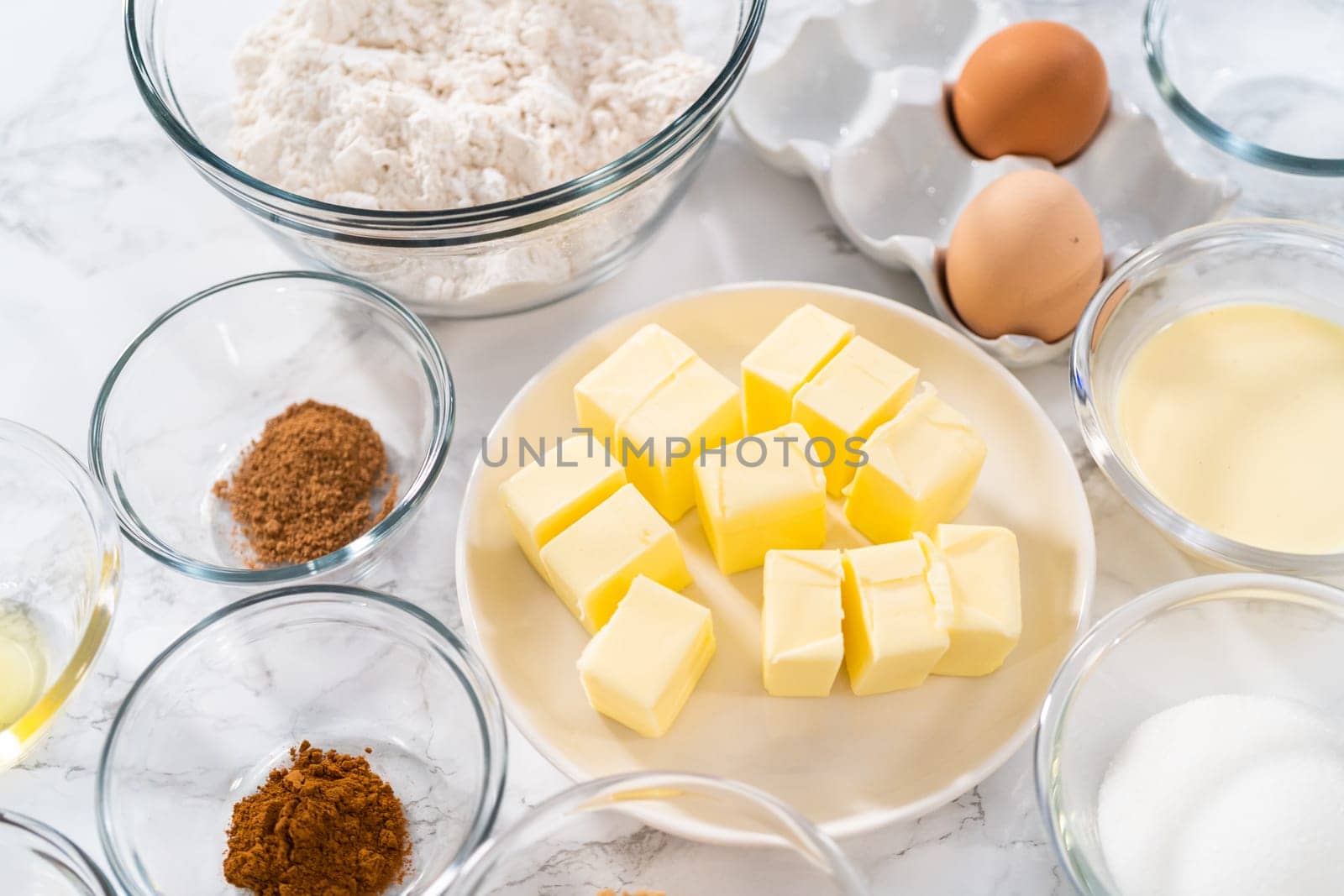 Measured ingredients in glass mixing bowls to bake eggnog cookies with a chocolate gingerbread man.