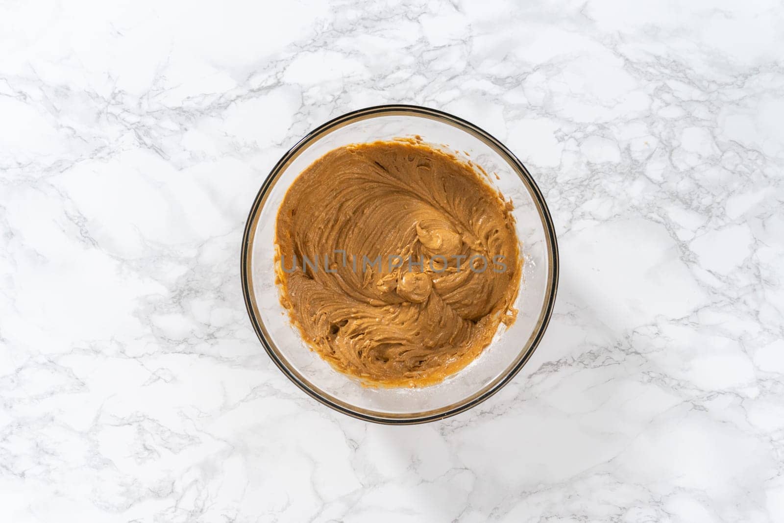 Mixing ingredients in a large glass mixing bowl to bake gingerbread cupcakes.