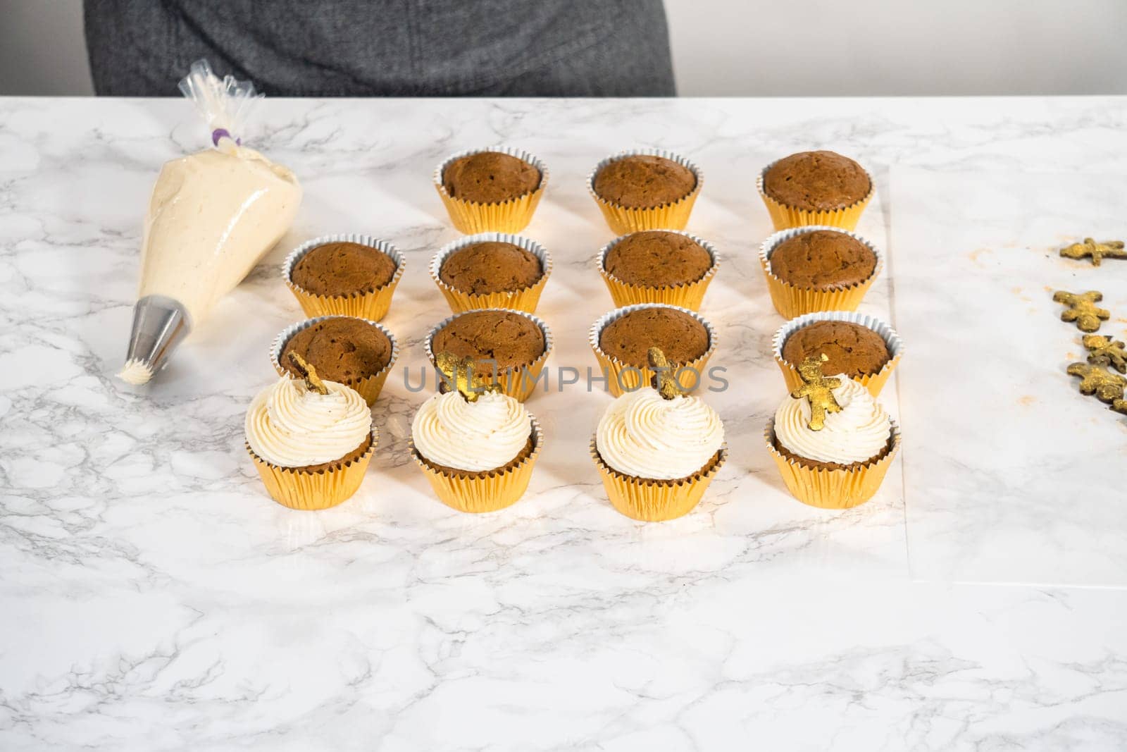 Piping eggnog buttercream frosting on top of gingerbread cupcakes and topping with a chocolate gingerbread man.