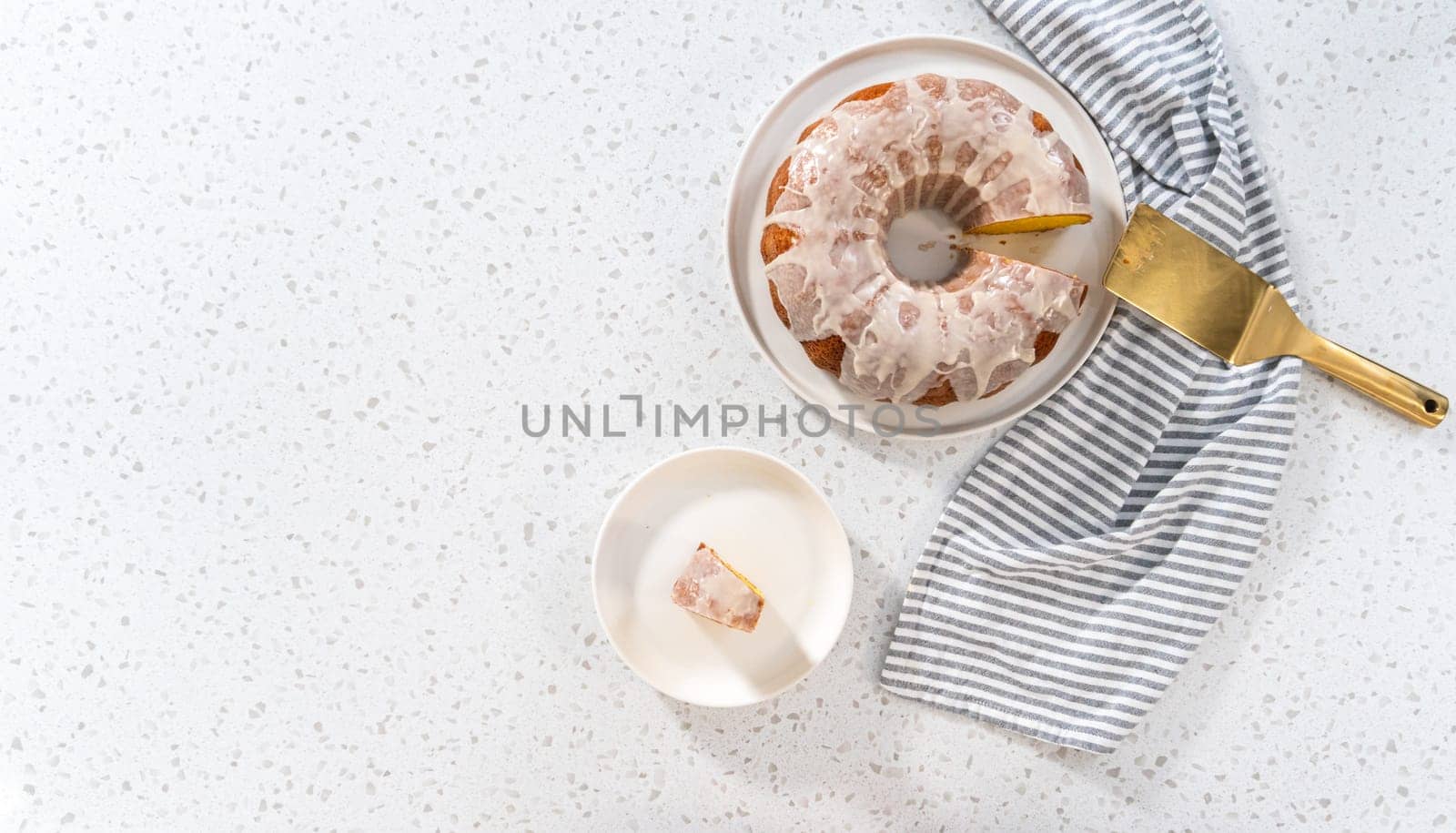 Flat lay. Sliced vanilla bundt cake with a vanilla glaze on a white plate.