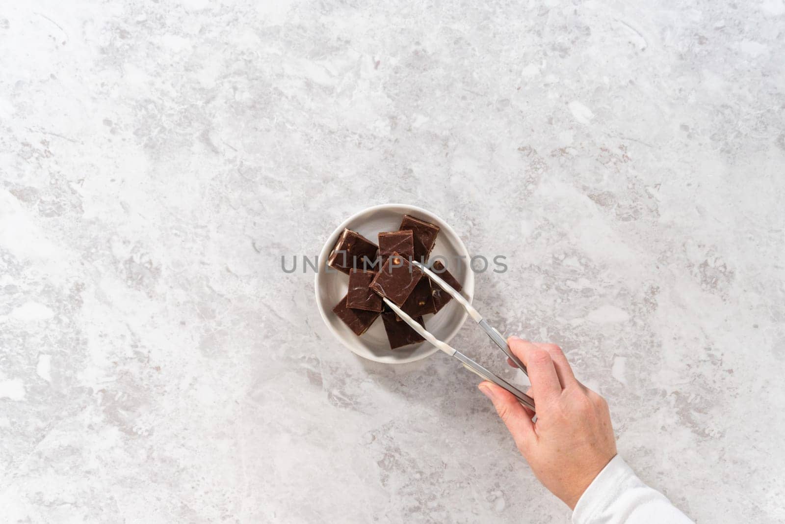 Flat lay. Homemade chocolate macadamia fudge square pieces on a white plate.