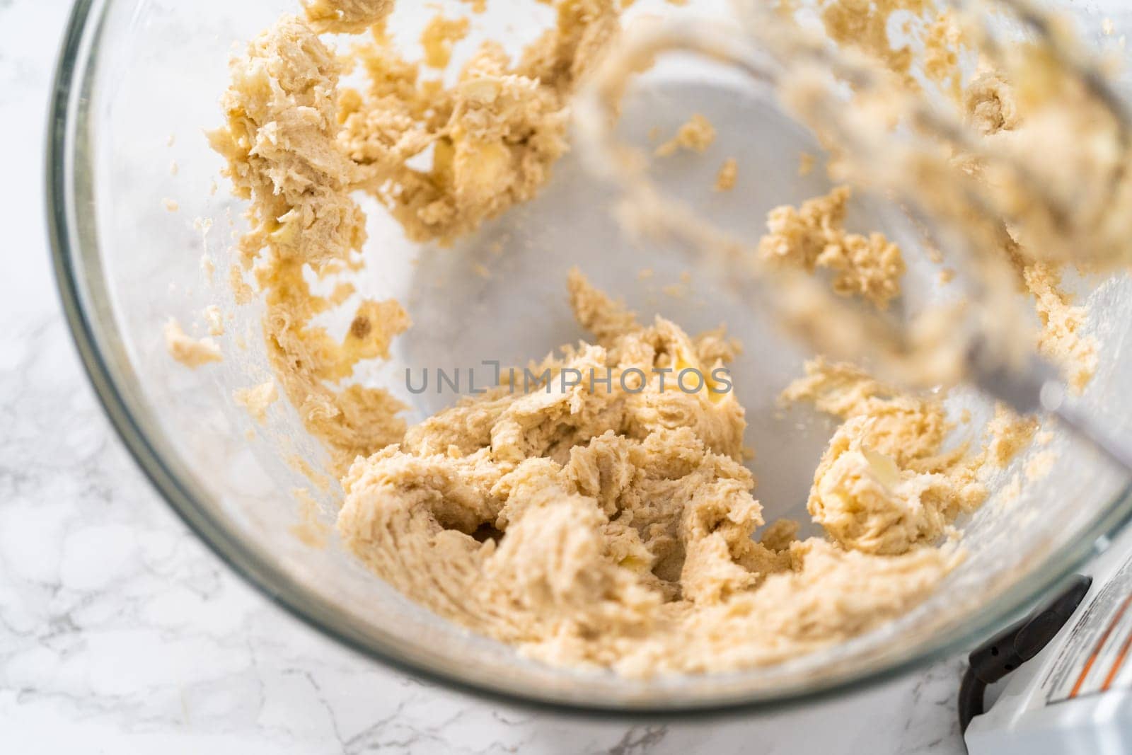 Mixing ingredients with a hand mixer to bake eggnog cookies with a chocolate gingerbread man.