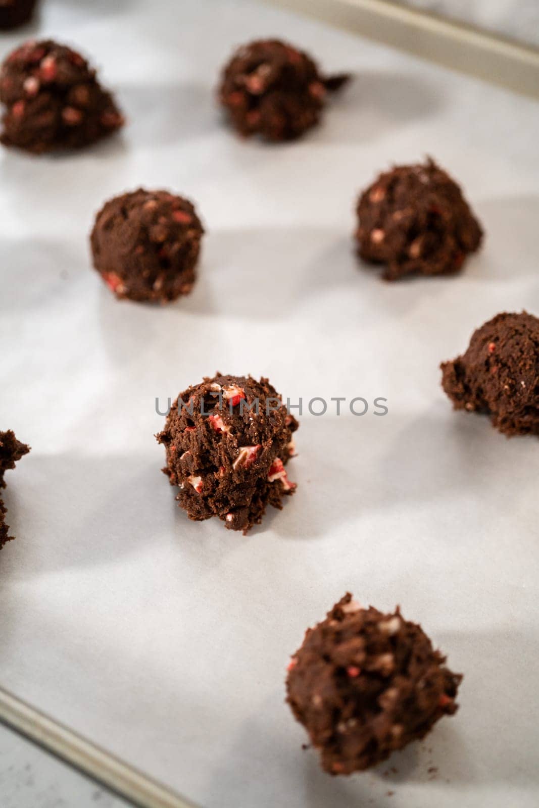 Scooping chocolate cookie dough with dough scoop to bake chocolate cookies with peppermint chips.